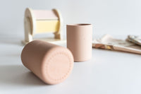 Two cylindrical childrens drinking cups on a light surface with a blurred background