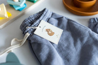 Blue drawstring bag with a tag on a light surface